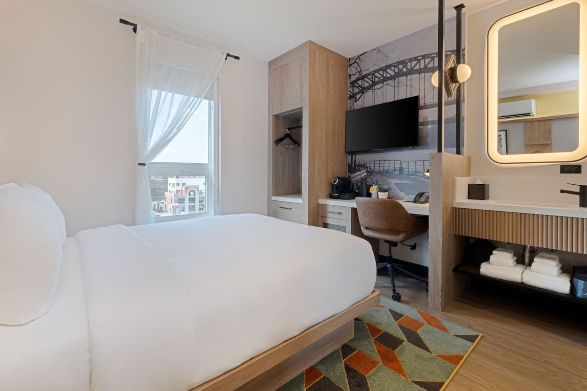 Une chambre d’hôtel équipée d’un lit, d’un bureau, d’une chaise, d’une télévision et d’une salle de bain.