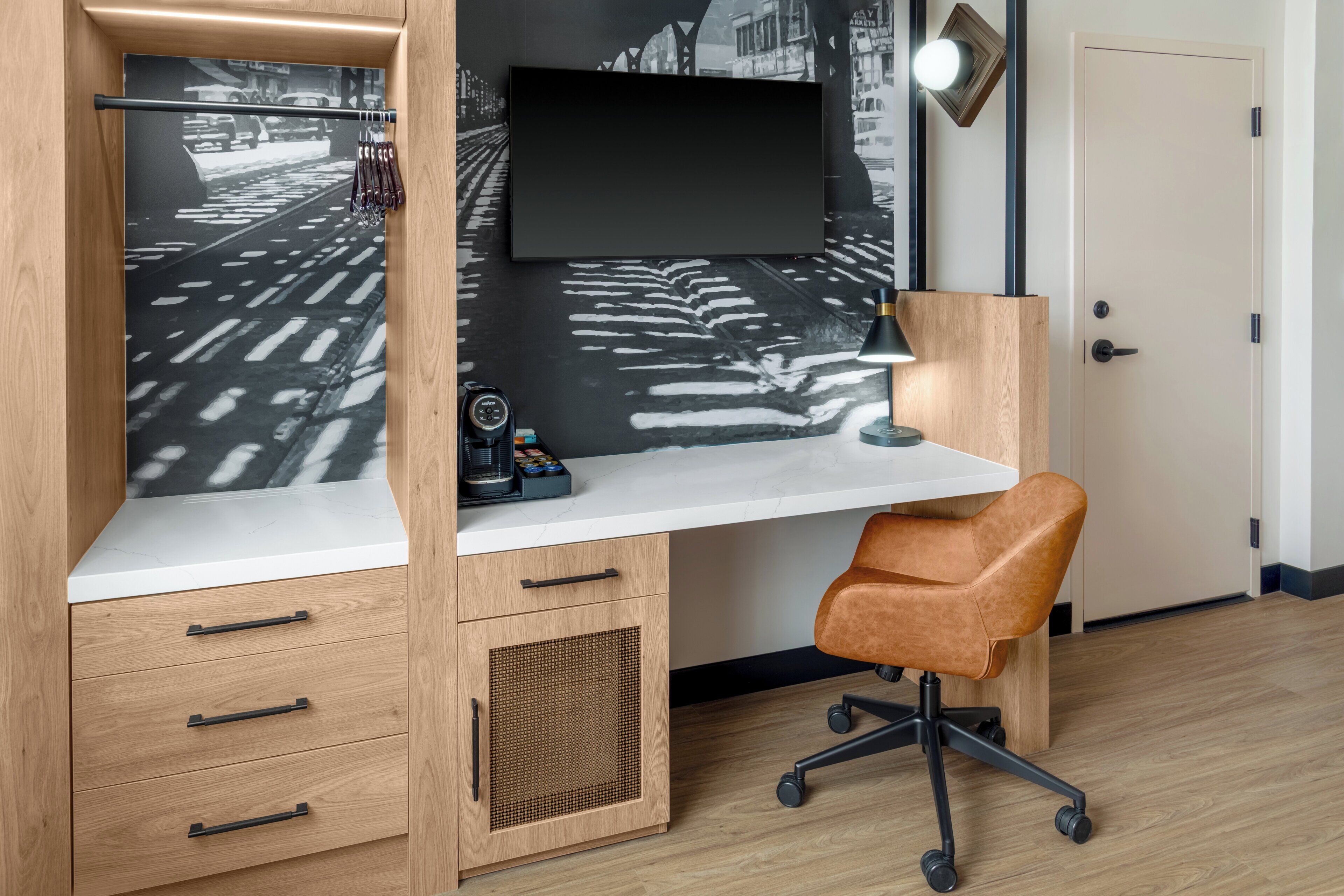 A modern office space with a white desk, a brown leather chair, and a large wall-mounted TV.
