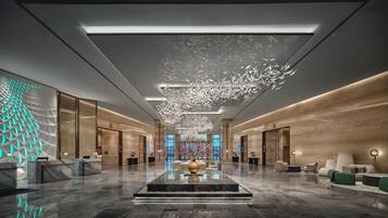 A spacious lobby with a central water feature, modern seating, and a geometric wall design.