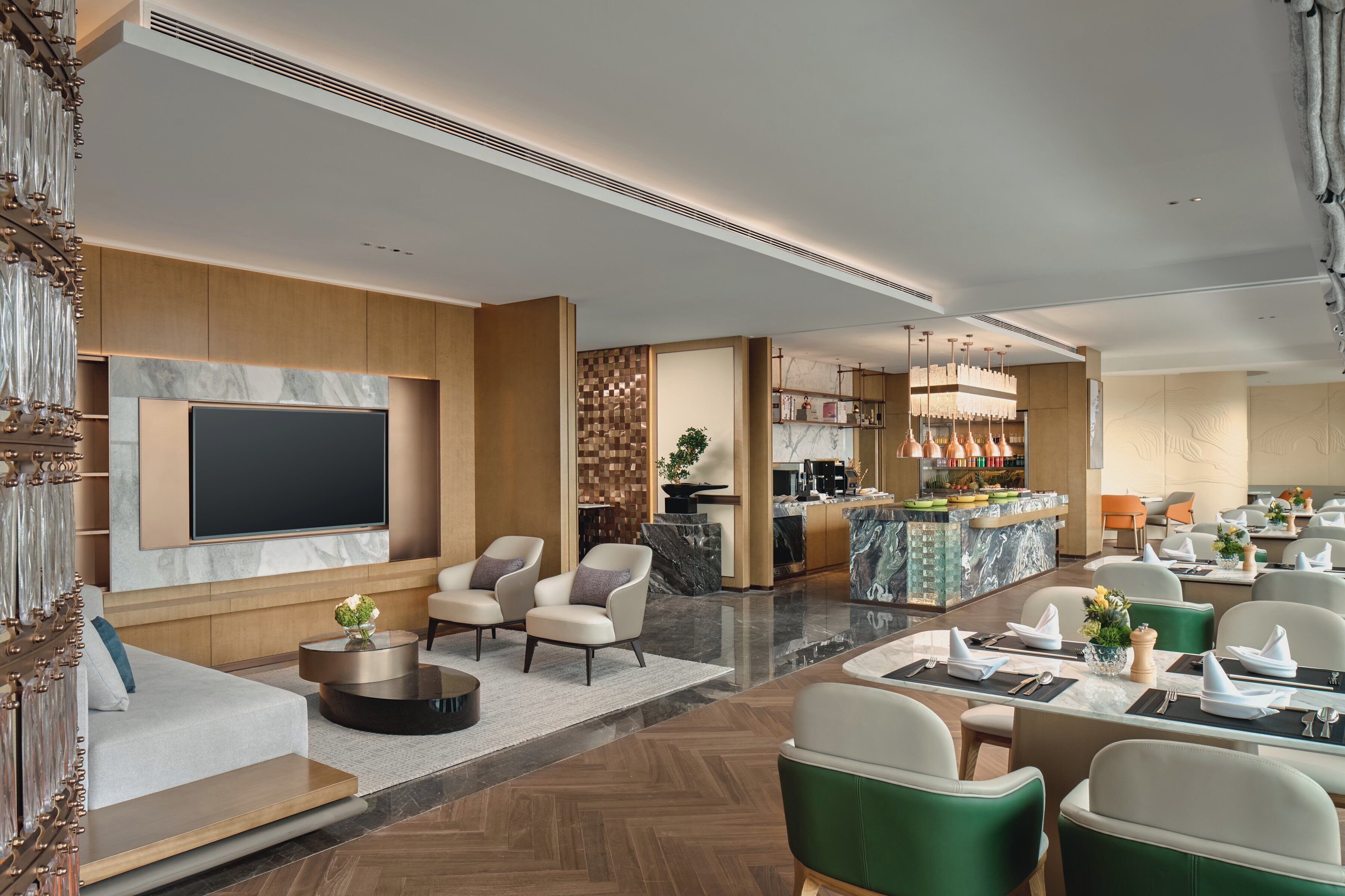 Um hall de hotel moderno com área de estar, bar e uma tela de televisão.