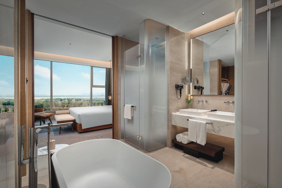 Un baño moderno con una bañera grande, dos lavamanos y una ducha con cerramiento de vidrio.