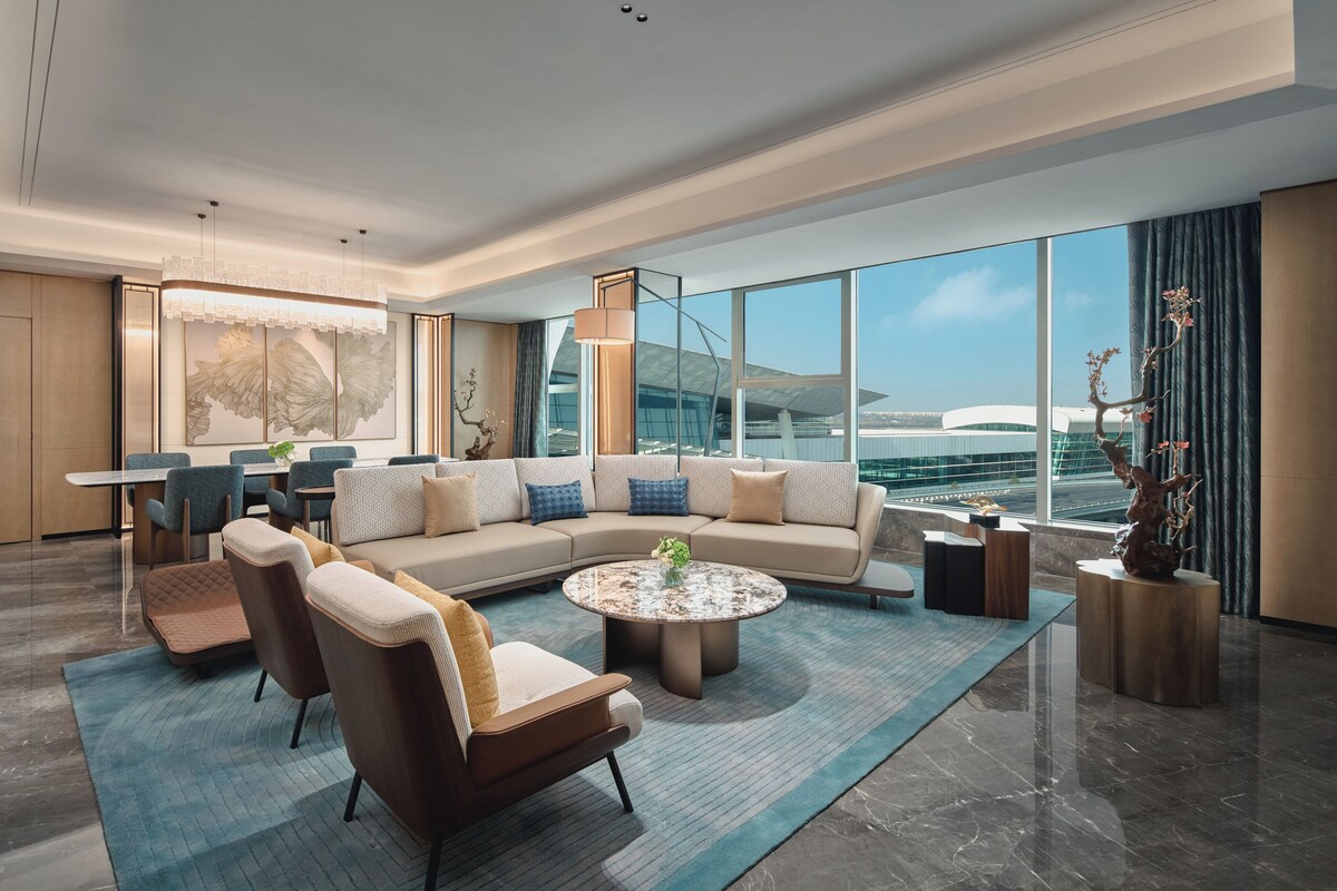 A modern living room with a sectional sofa, a round coffee table, and a dining area with chairs and a table.