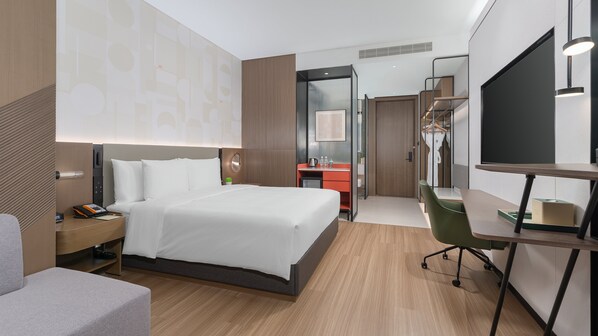 A hotel room with a bed, a desk, a chair, a wardrobe, and a mirror. - EVEN Hotel Wuhan Airport Zone by IHG (Wuhan)