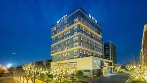 Un hotel de varios pisos con fachada de vidrio moderna, con la leyenda 'I EVEN'.
