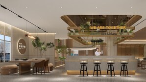 Un moderno vestíbulo de hotel con un mostrador de recepción central, zona de estar y un letrero que dice 