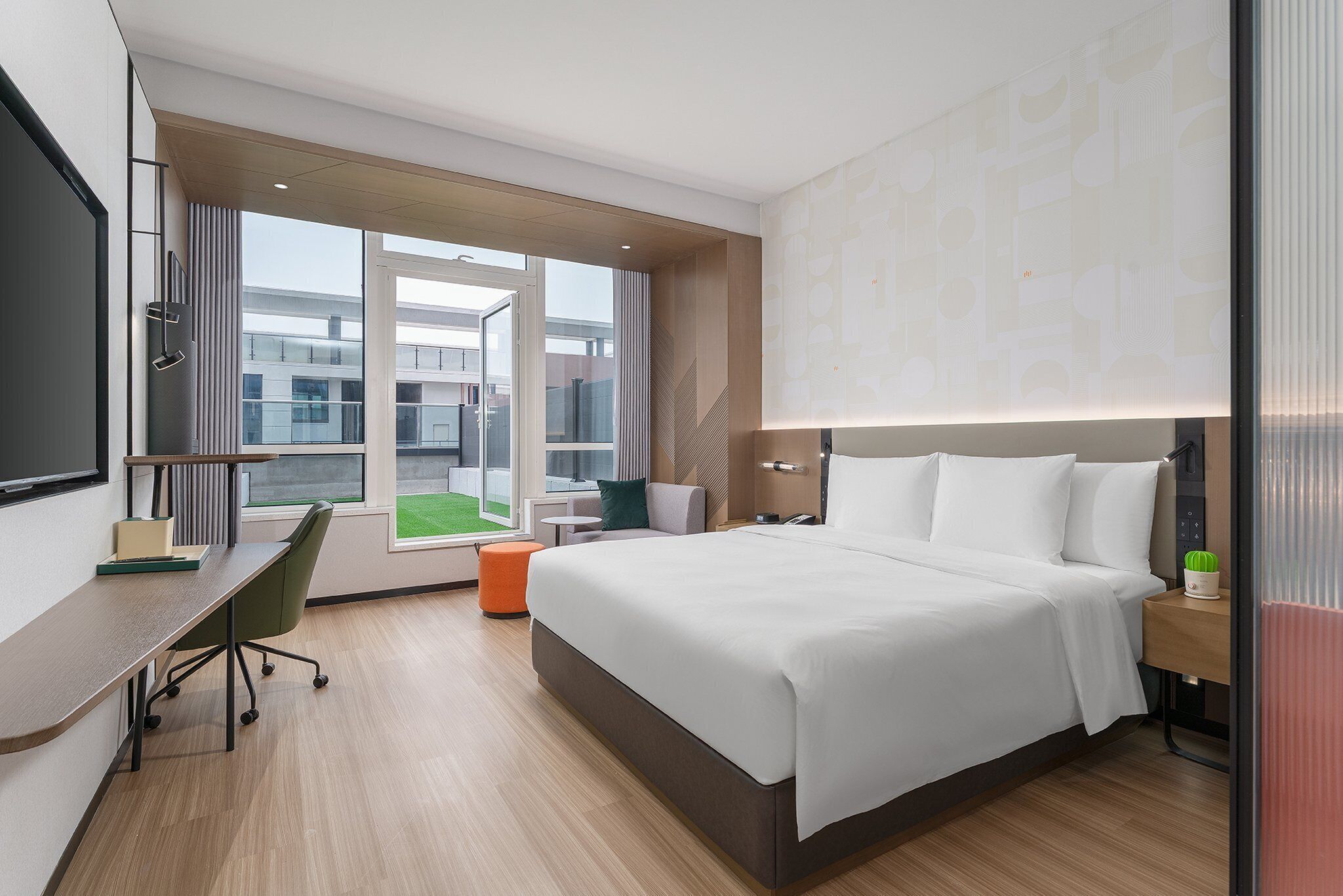 Een moderne hotelkamer met een groot bed, een bureau, een stoel en uitzicht op het buitengebied.