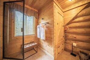 A wooden cabin bathroom with a bench, a towel rack, a toilet, and a window with blinds. - Gemini cabin, deck views of 14kft mtn, 40 min to Breck. Surrounded by wildlife (Fairplay)
