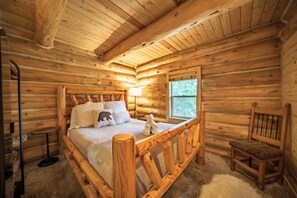 A wooden cabin bedroom with a bed, a chair, a lamp, and a window. - Gemini cabin, deck views of 14kft mtn, 40 min to Breck. Surrounded by wildlife (Fairplay)