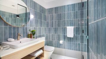 A modern bathroom with a large mirror, white sink, and a glass shower enclosure.