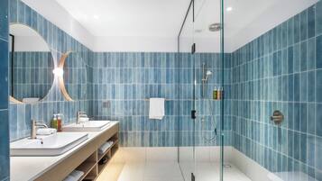 Un baño moderno con dos lavamanos, cabina de ducha de vidrio y un espejo grande.