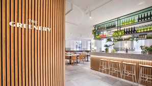 Un espace bar moderne agrémenté d’éléments en bois, un comptoir avec des tabourets et des étagères remplies de bouteilles.