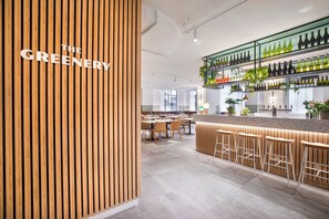 Un espace bar moderne agrémenté d’éléments en bois, un comptoir avec des tabourets et des étagères remplies de bouteilles.