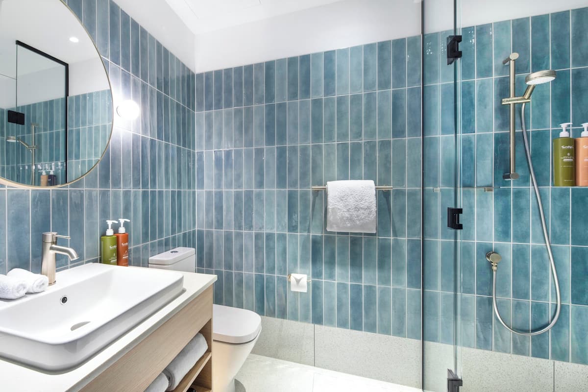 Une salle de bain moderne avec un grand miroir, un lavabo, des toilettes et un espace douche.