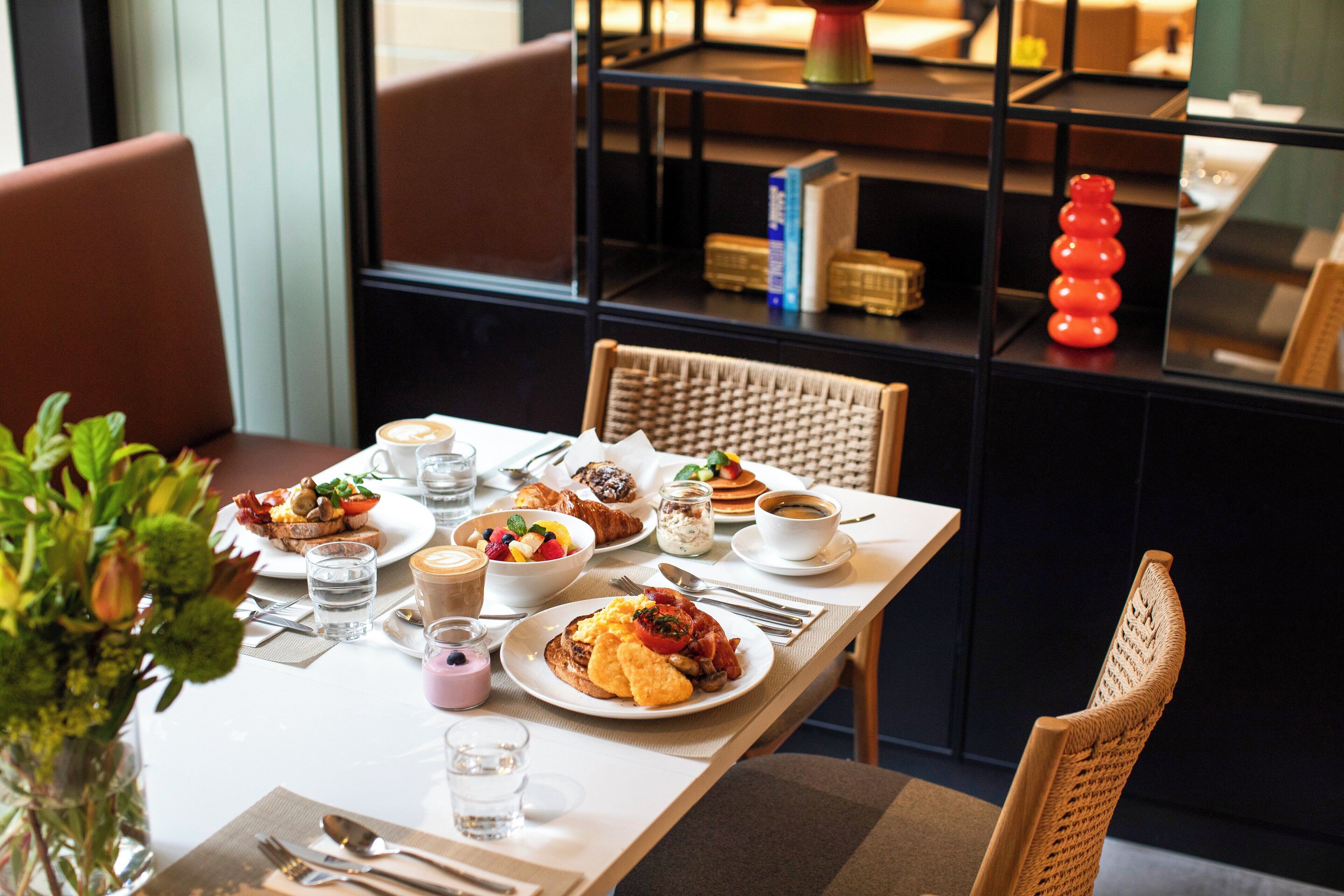 A breakfast setting with various dishes, including toast, pancakes, and a fruit bowl.