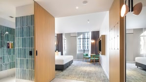 Een moderne hotelkamer met een douche, een bed, een bureau en uitzicht op de stad.