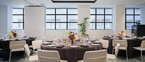 A conference room with round tables, chairs, and a large window with a view.
