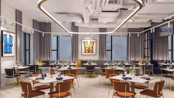 A modern dining area with multiple tables and chairs, large windows, and contemporary artwork.