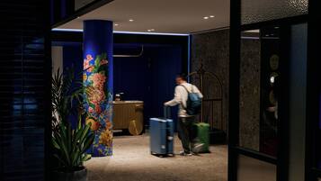A hotel lobby with a large pillar, a reception desk, and a person with luggage.