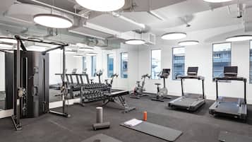 A modern gym with exercise equipment, large windows, and a clean, bright interior.