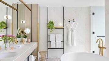 Un baño moderno con una bañera grande, un tocador doble y un espejo, además de un perchero con varias toallas.