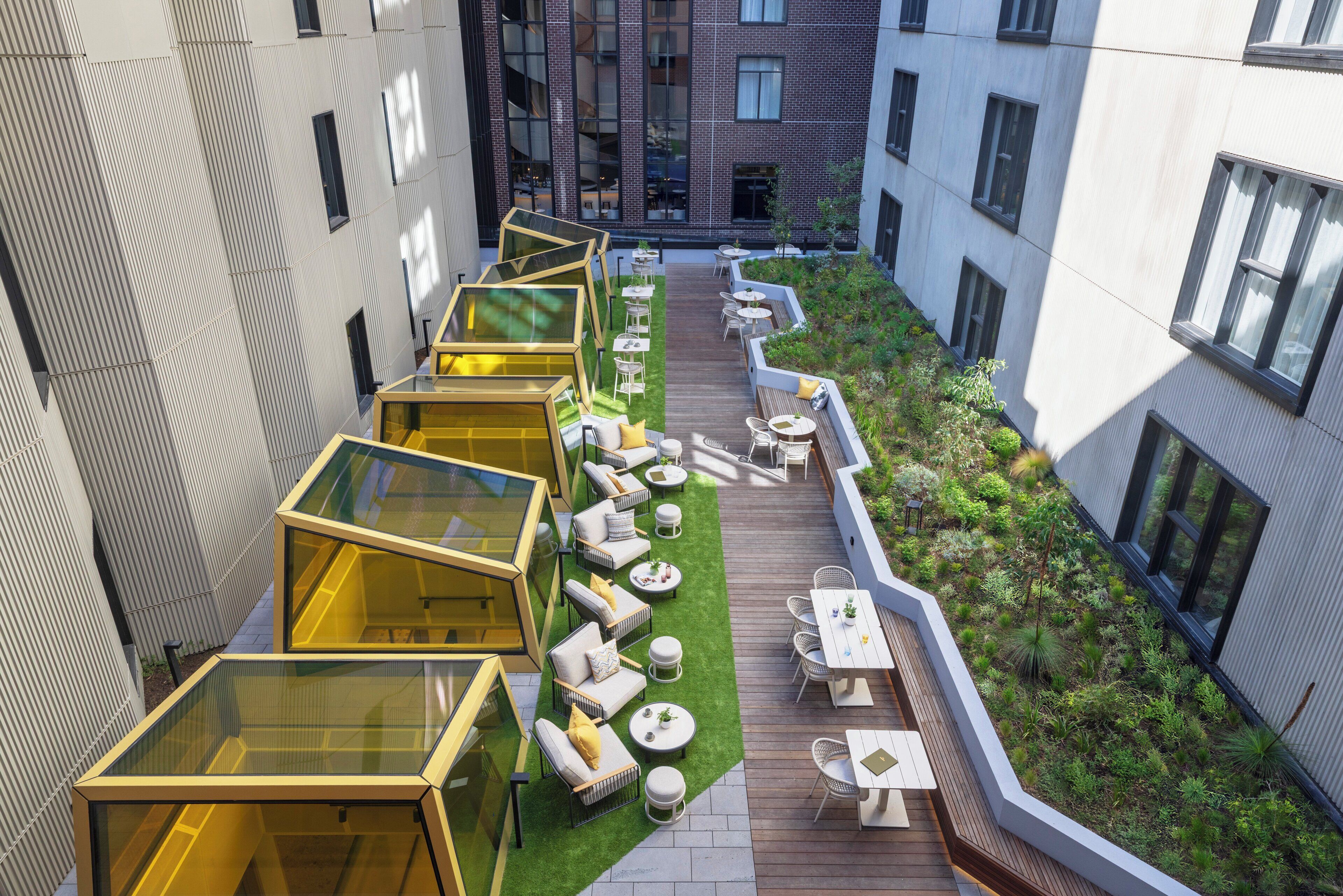 A rooftop garden with seating areas and glass structures.