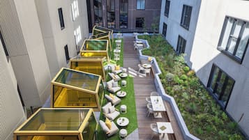 A rooftop garden with seating areas and glass structures.
