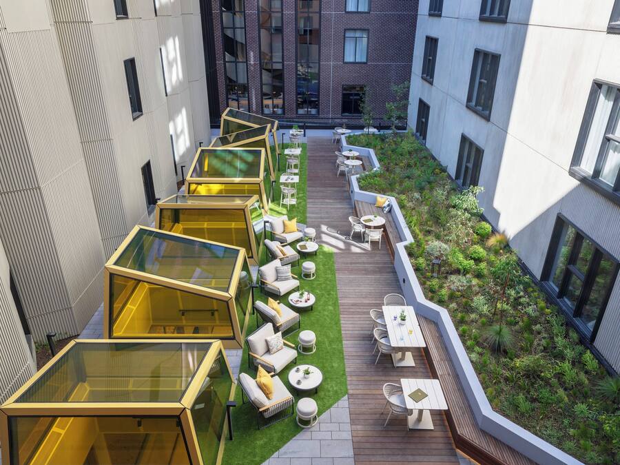 A rooftop garden with seating areas and glass structures.