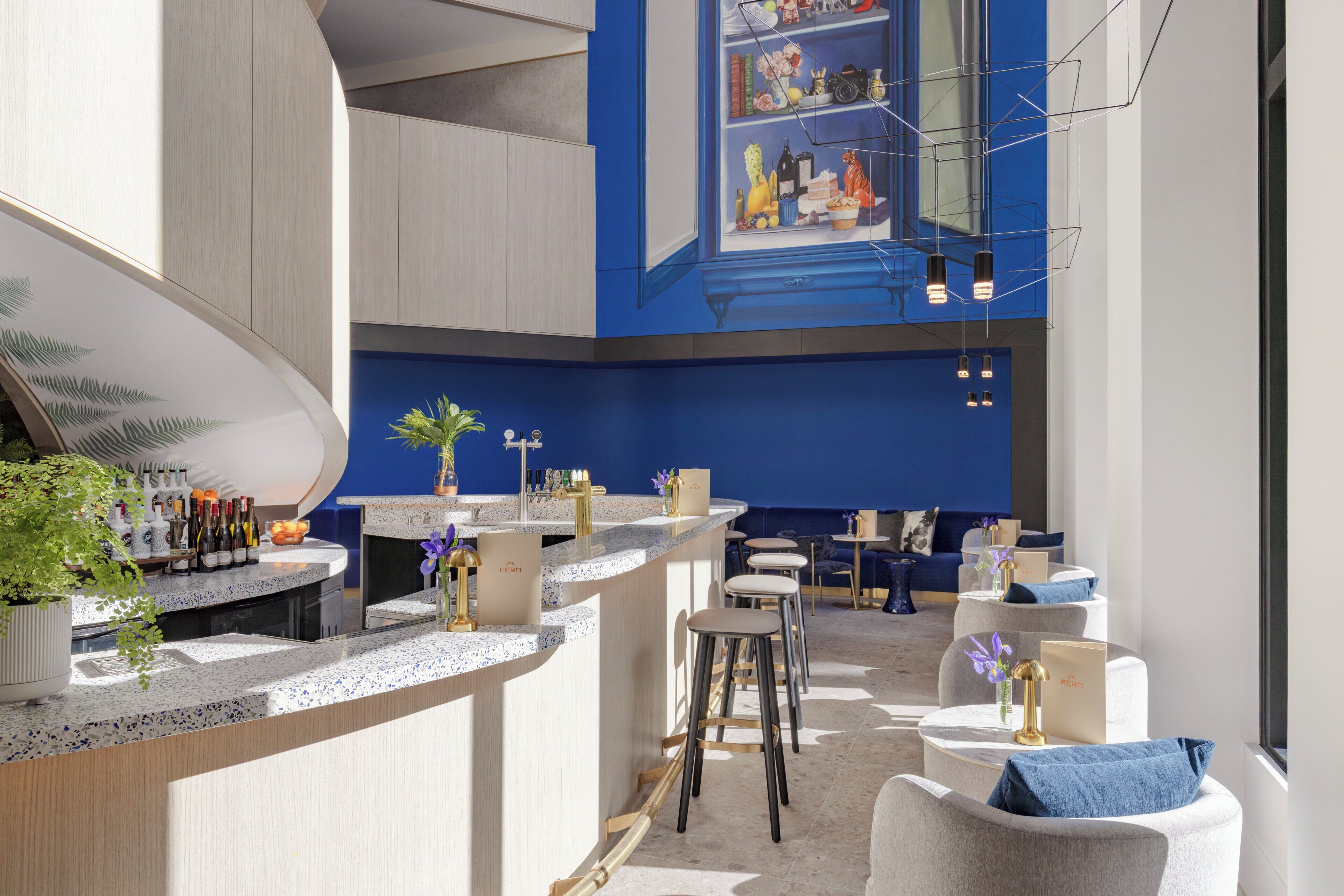 A modern bar area with a curved counter, bar stools, and a seating area with round tables and chairs.