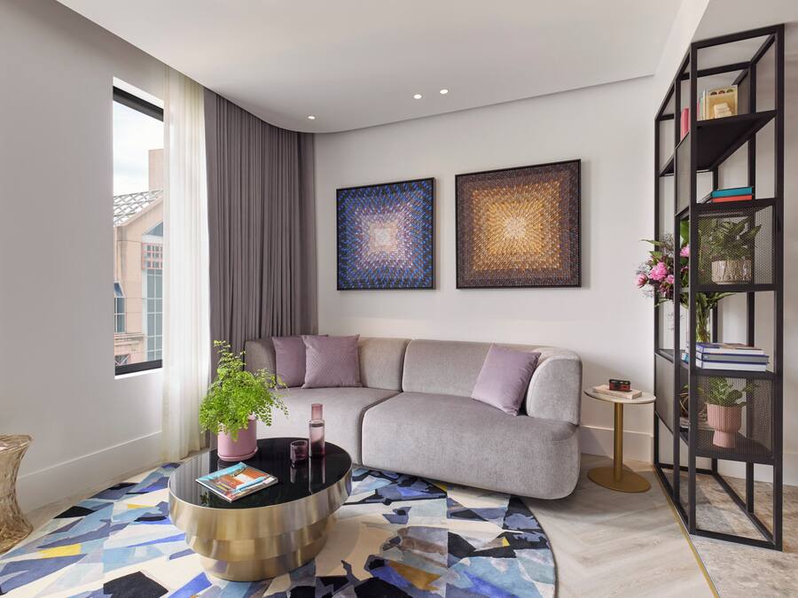 A modern living room with a grey sofa, a round coffee table, and two abstract paintings on the wall.