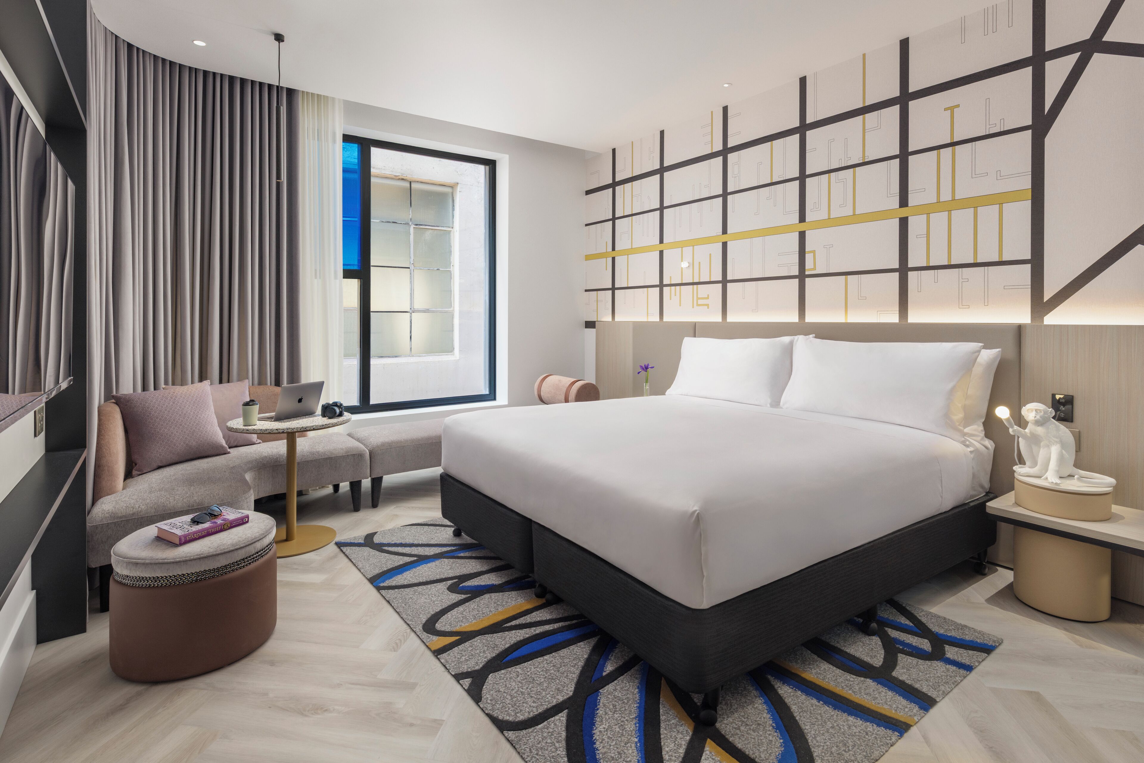 Une chambre d’hôtel moderne, dotée d’un grand lit, d’un canapé, d’un bureau et d’une fenêtre avec des rideaux.