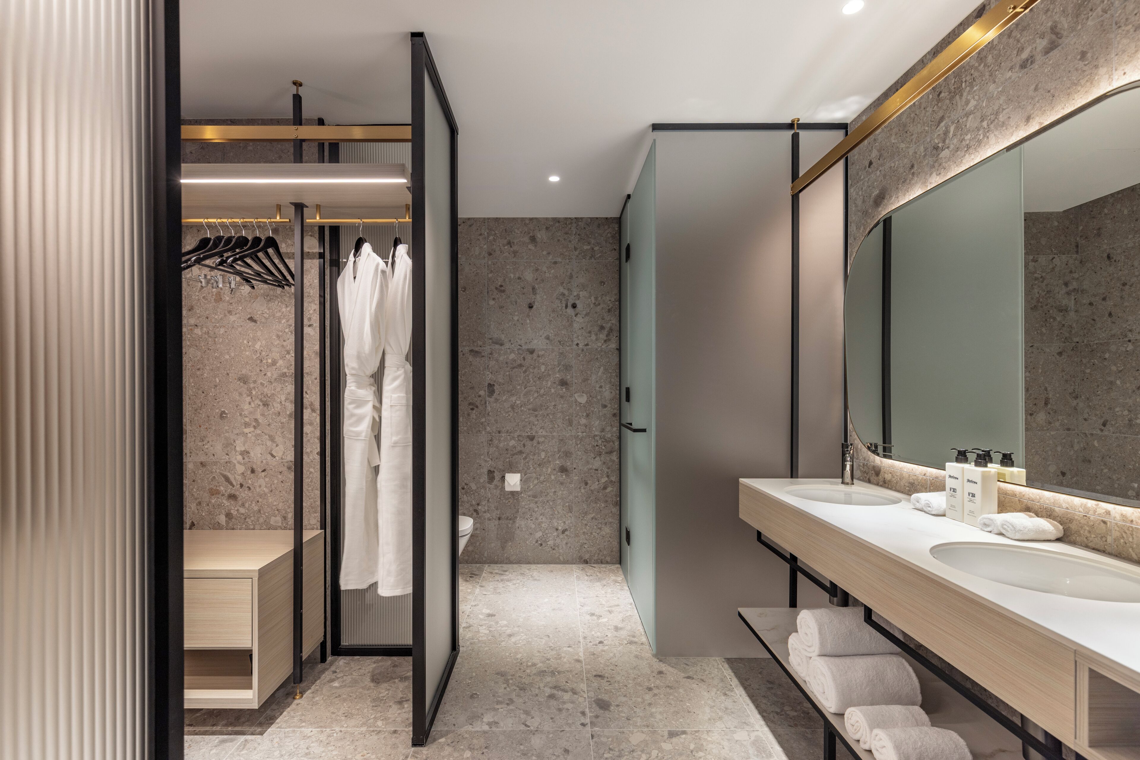 Un baño moderno con ducha a ras de suelo, un espejo grande y un tocador con dos lavabos.