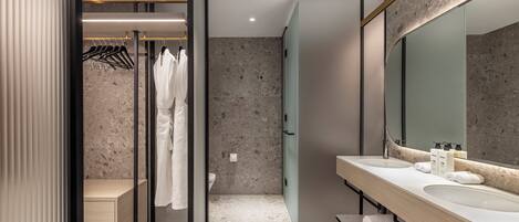 Un baño moderno con ducha a ras de suelo, un espejo grande y un tocador con dos lavabos.