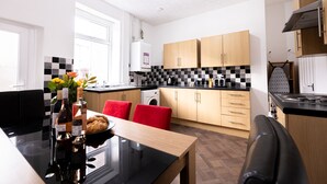 Et moderne køkken med et skakmønstret bagpanel i sort og hvid, træskabe og et spiseområde med bord og stole.