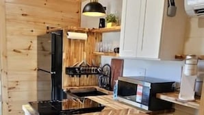 A kitchen with wooden ceiling, a central island with stools, a microwave, and a coffee machine. - Eagle Nest Cabin B at Walterfalls – Upstate SC (Six Mile)