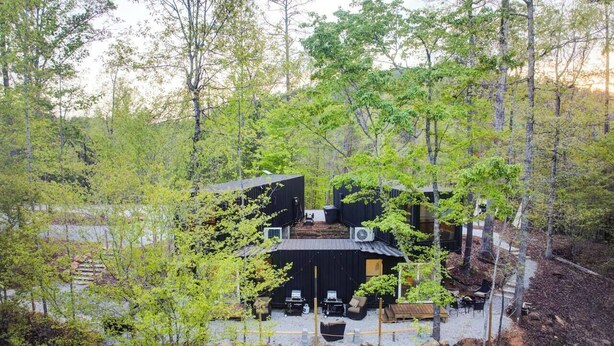 A modern cabin with a black exterior, surrounded by a forested area. - Eagle Nest Cabin B at Walterfalls – Upstate SC (Six Mile)