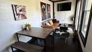 A modern interior with a wooden ceiling, a sofa, a table, and artwork on the walls. - Eagle Nest Cabin B at Walterfalls – Upstate SC (Six Mile)