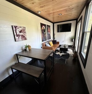 A modern interior with a wooden ceiling, a sofa, a table, and artwork on the walls. - Eagle Nest Cabin B at Walterfalls – Upstate SC (Six Mile)
