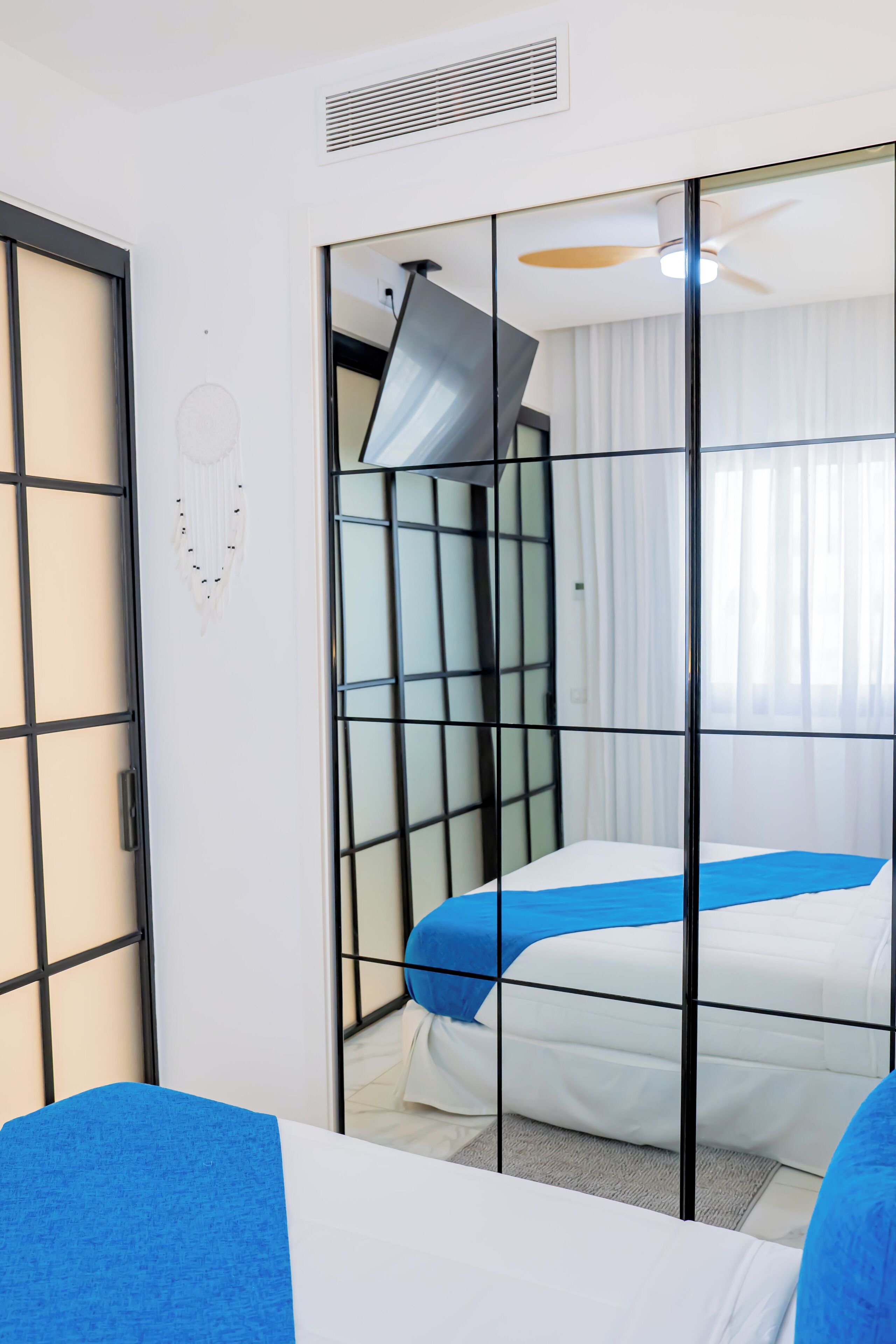 A hotel room with a bed, a ceiling fan, and a window with curtains.