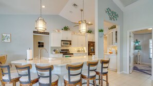 A modern kitchen with a central island, bar stools, and pendant lighting.
