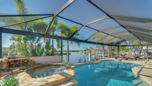 A swimming pool with a stone edge and a view of the water.