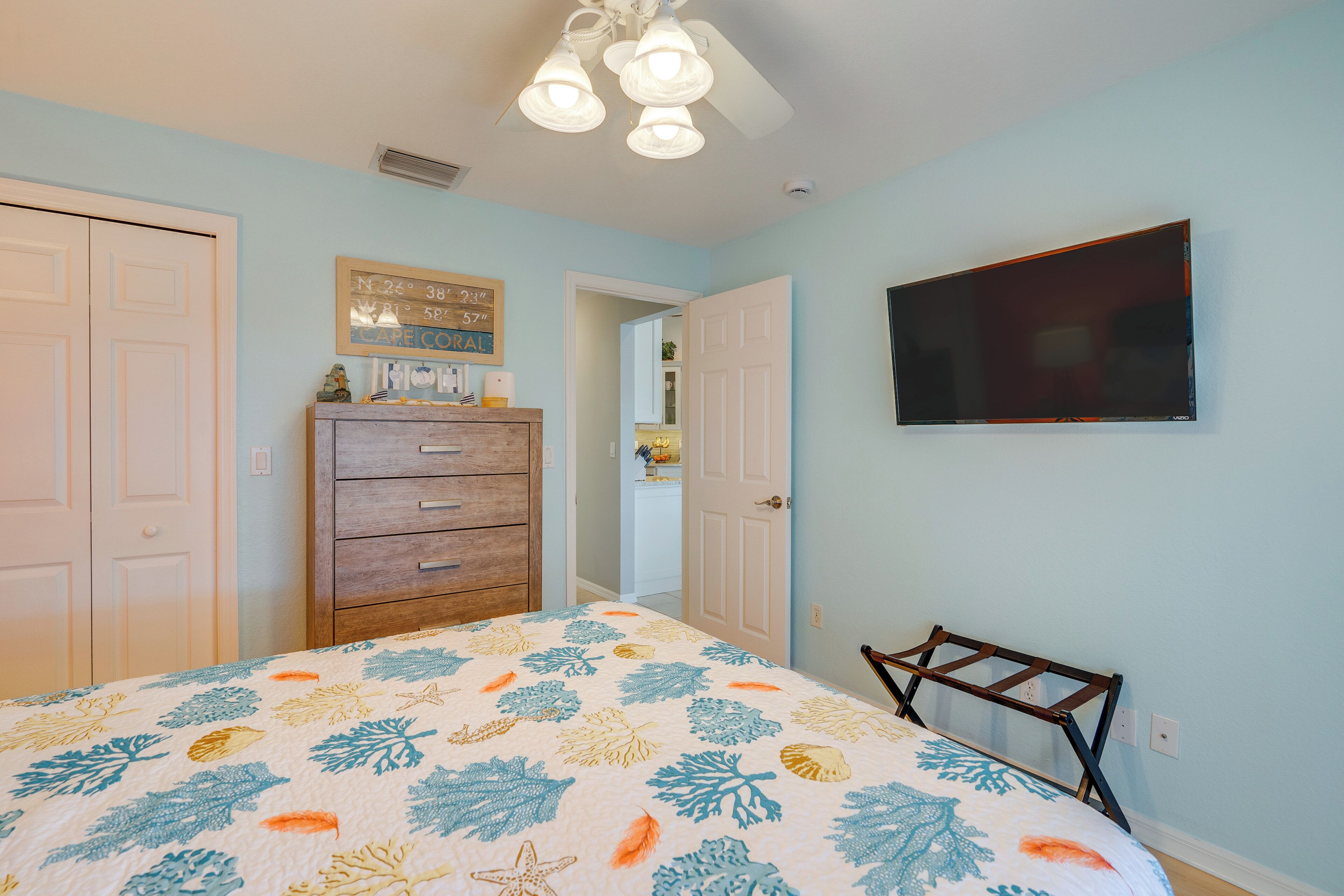Une chambre à coucher avec un lit, une commode et un téléviseur fixé au mur.