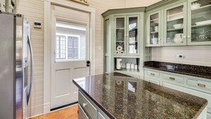 Cocina con encimera de granito, muebles blancos y refrigerador de acero inoxidable.