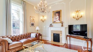 Una sala de estar con un sofá de cuero, una mesa de centro de vidrio, una chimenea, un televisor y apliques de pared.