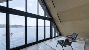 Quarto espaçoso com amplas janelas que oferecem vista para um lago e caiaques.