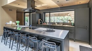 Cozinha moderna com uma ilha grande, banquetas e vista para o verde lá fora.