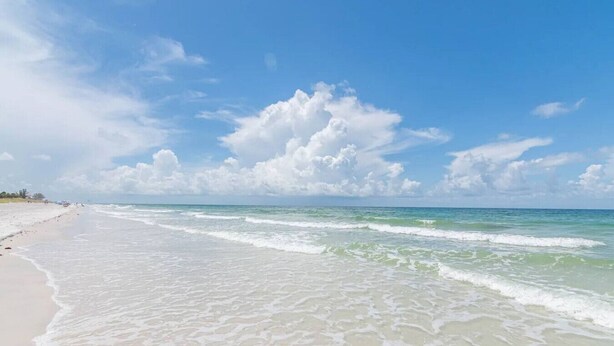 Ein Strand mit blauem Himmel und sanften Wellen.