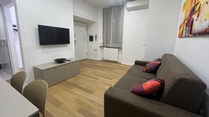 En moderne stue med en grå sofa, et fladskærms-tv og trægulv.