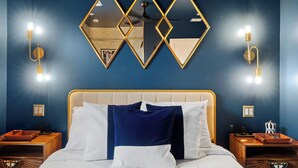 A neatly made bed with white and blue pillows, a wooden headboard, and a wall with geometric mirrors and wall sconces. - Sexy Boutique Estate in Fun Size - Swank Chill Vibe - Mill Ave - Spring Training (Tempe)
