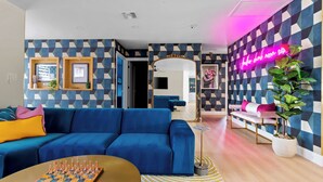 A modern living room with a blue sofa, a chessboard, and a neon sign. - Sexy Boutique Estate in Fun Size - Swank Chill Vibe - Mill Ave - Spring Training (Tempe)