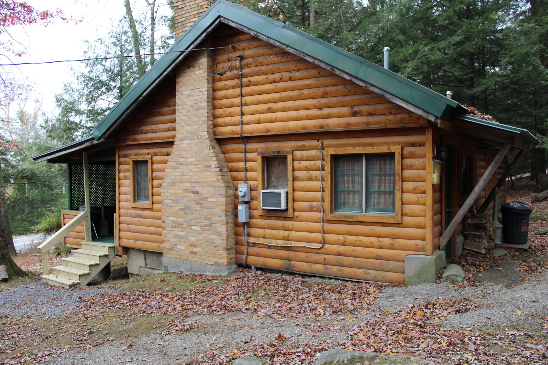 Une cabane en rondins avec une cheminée, un petit porche et un escalier menant à l’entrée.